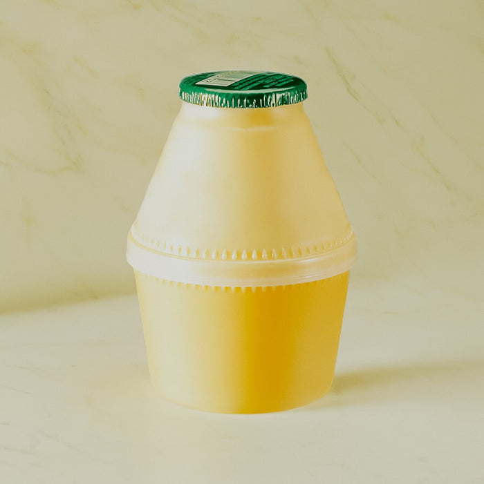 A yellow container with a green lid, resembling a bottle of banana milk.