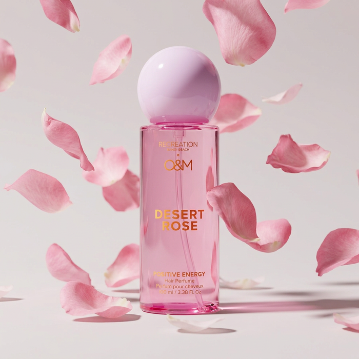 Perfume bottle labeled 'Desert Rose' with pink petals on a light background