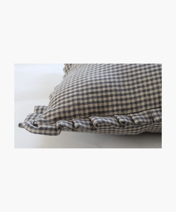 A detailed picture of a pillow highlightings its black and white gingham pattern and ruffled edges, conveying a classic and cozy feel, set against a plain background. | Wildwood Home Co.