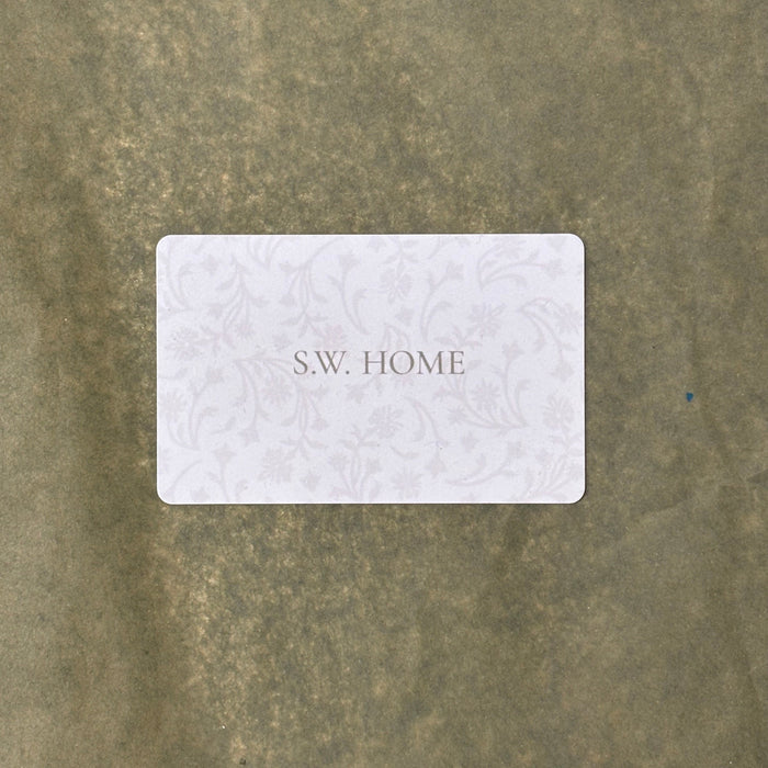 White gift card with 'S.W. HOME' text on a textured sage background