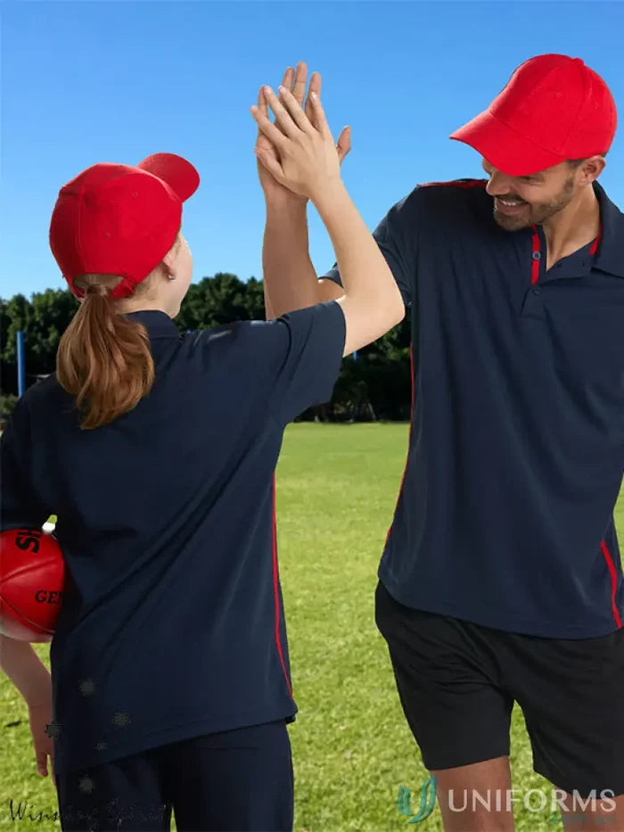 Two people in navy blue polo shirts and red caps high-fiving on grass, 10x Bundle Cap