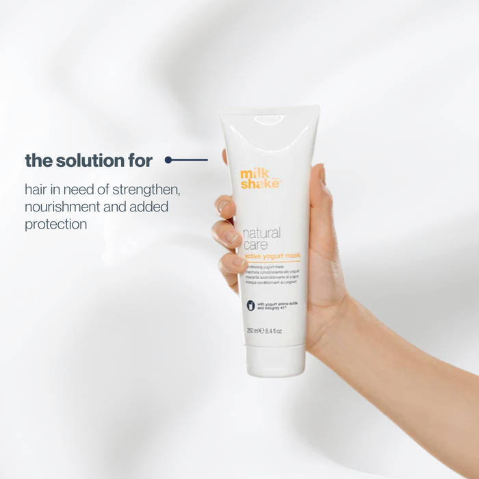 Hand holding a bottle of 'milk_shake' natural care product against a white background