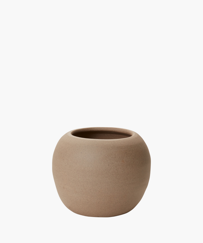 A round, light brown ceramic pot with a smooth, matte texture is centered on a plain white background. The pot exudes simplicity and elegance. | Wildwood Home Co.