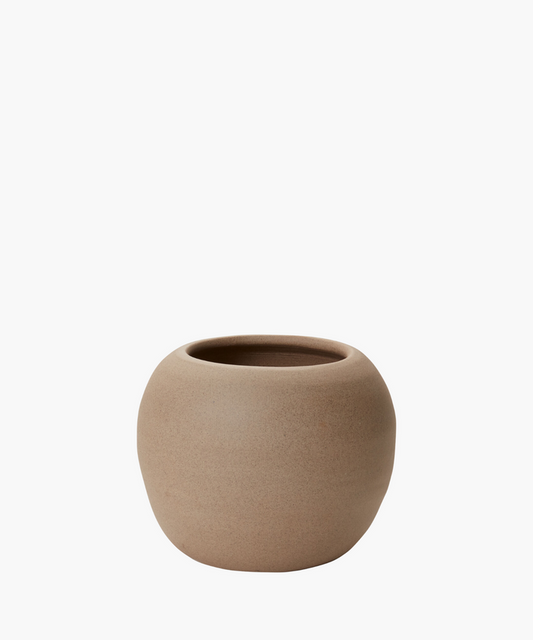 A round, light brown ceramic pot with a smooth, matte texture is centered on a plain white background. The pot exudes simplicity and elegance. | Wildwood Home Co.