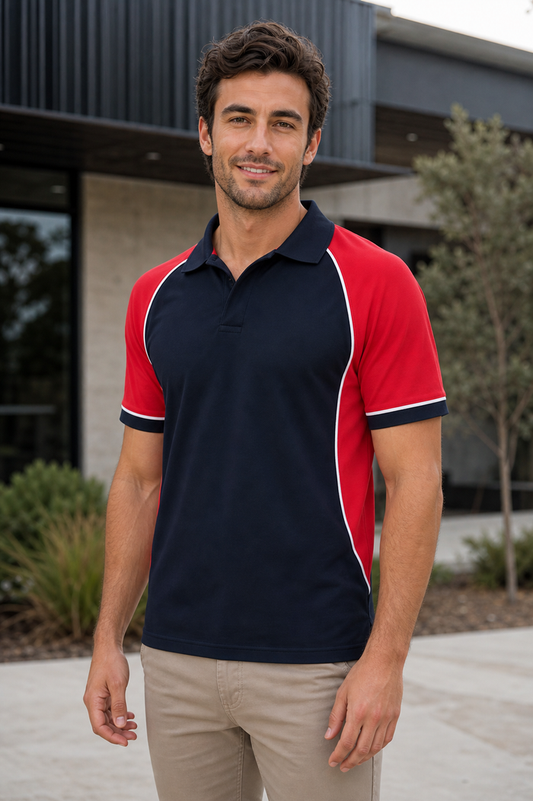 A man wearing a short-sleeve polo shirt with a navy blue body and red sleeves, accented by thin white piping, paired with khaki pants, standing outdoors in front of a modern building.