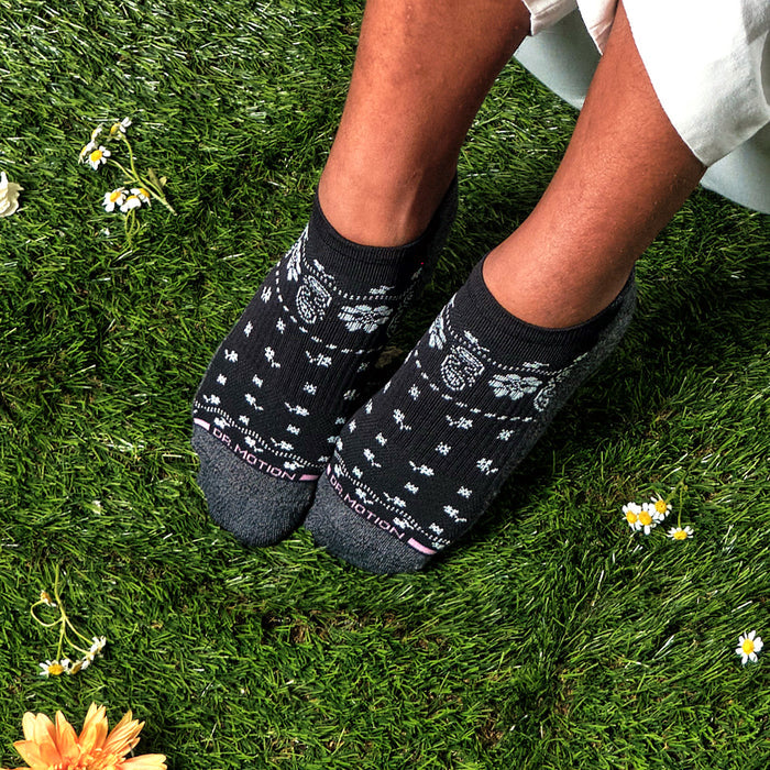 Black ankle compression socks with floral pattern and gray accents, worn on feet against a grassy background.