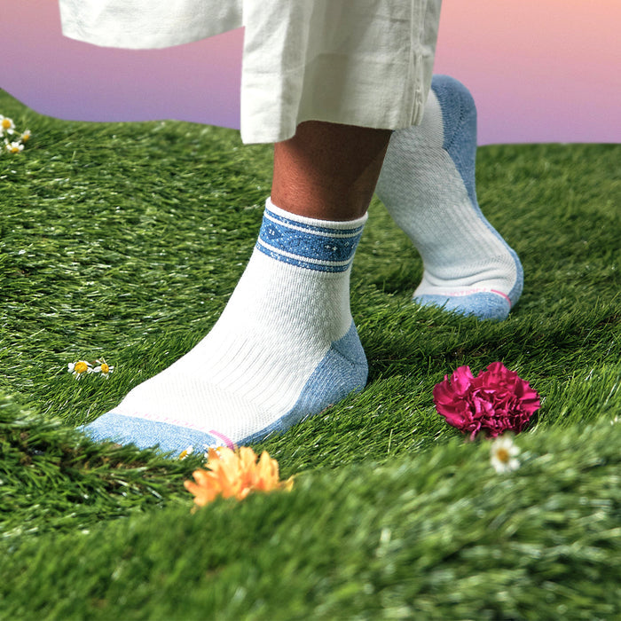 Quarter compression socks with a blue and white bandana stripe design, worn on grass with flowers.