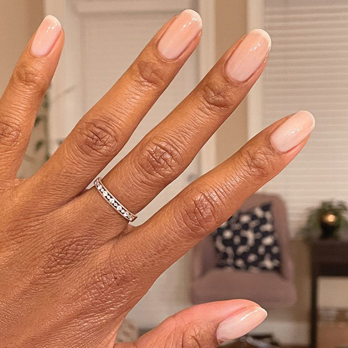Hand with nails painted in sheer BEB gel polish showing a natural and elegant manicure on warm skin tone