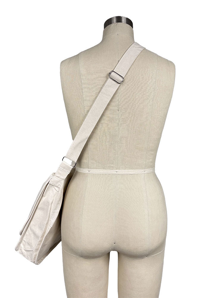 Back view off-white canvas bag displayed on a mannequin against a plain background.