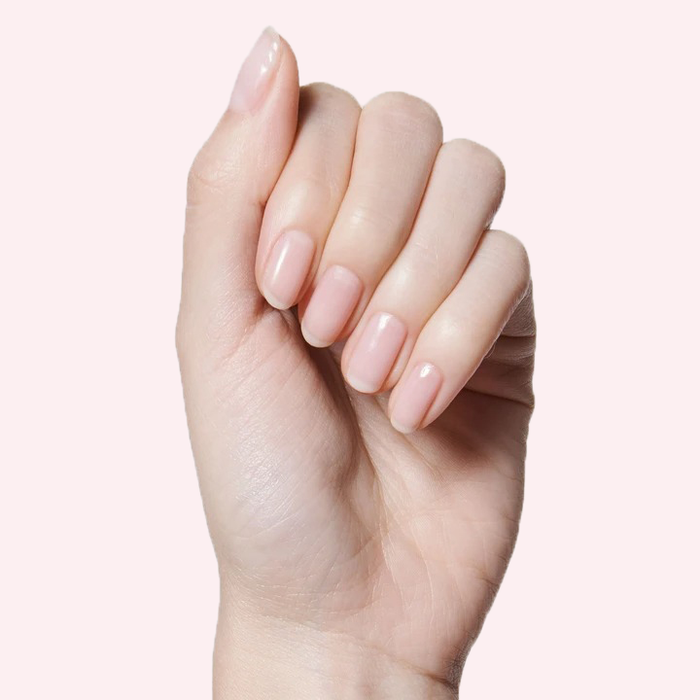 Hand with nails painted in CCT sheer neutral pastel pink polish for a soft and natural mani look