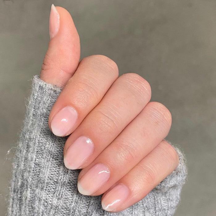 Hand with natural nails polished in CCT sheer neutral pastel pink for a subtle and elegant manicure look