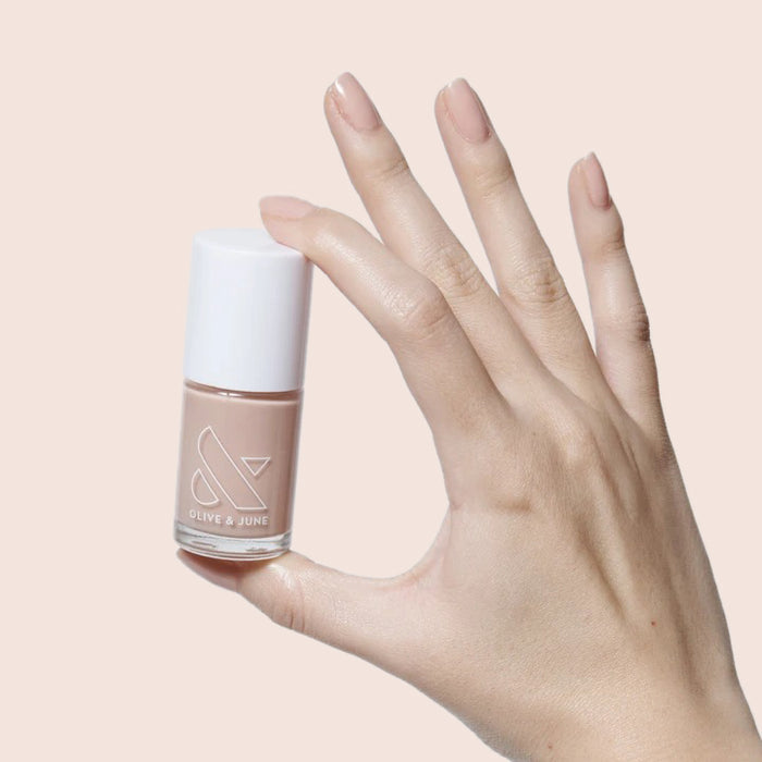 Hand holding bottle of CHM sheer tan gel polish for a natural and flattering manicure look