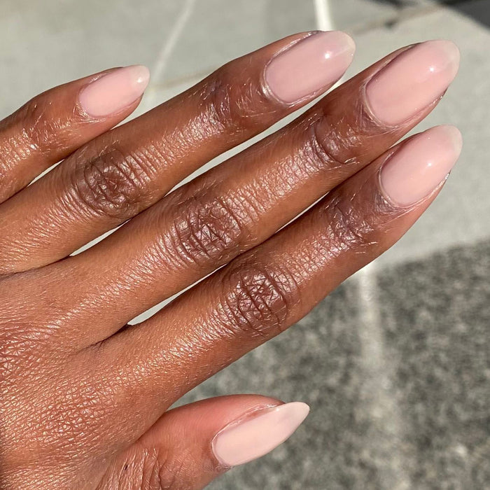 Hand with nails coated in CHM sheer tan gel polish for a simple and elegant manicure look at home