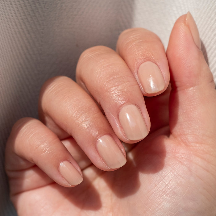 Hand with nails coated in CHM sheer tan gel polish for a natural and polished at-home manicure look