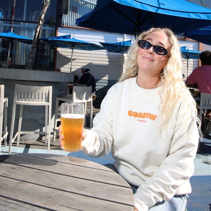 Woman holding a beer at an outdoor cafe with 'Broads' sign in the background