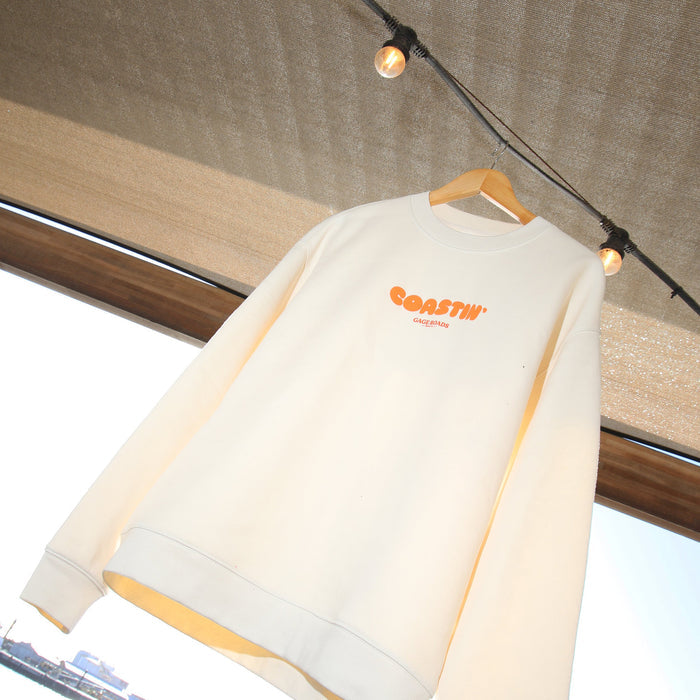 White sweatshirt with orange logo on a hanger against a cityscape background