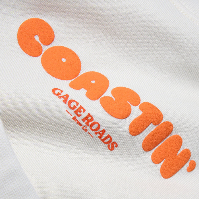 Orange 'Coastin'' text on a white jumper