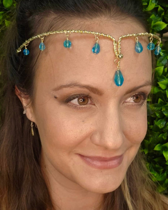 Gold wire forehead band with blue crystal drop accents worn on head