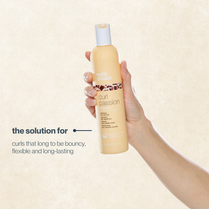 Hand holding a bottle of milk_shake curl passion' product with a beige background