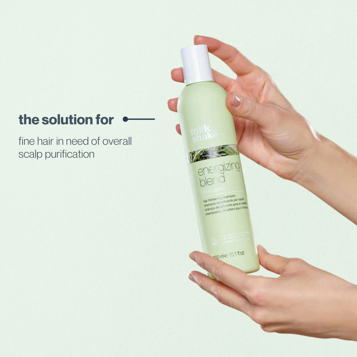 Hand holding a bottle of 'milk_shake energizing blend' product with text on a light background
