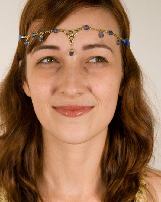 Model wearing Eternity Tie-On Crown and Necklace with gold ribbon, Celtic trinity knot centerpiece, and blue crystal bead accents, front view.