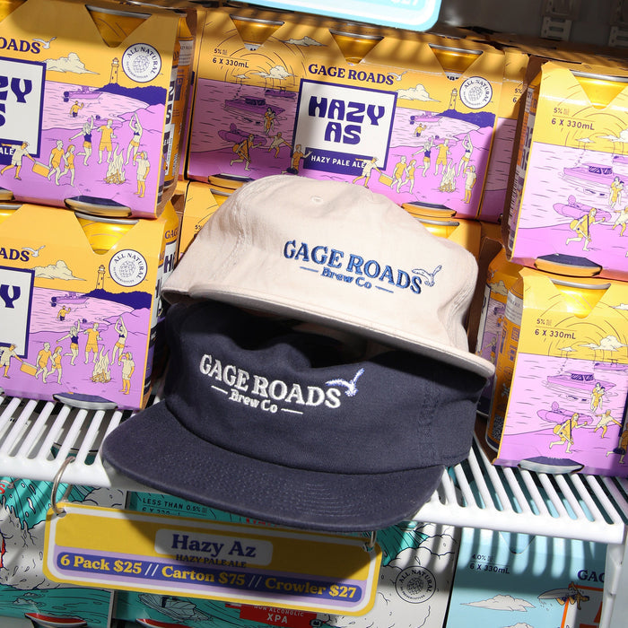 Two hats with 'Gage Roads Brew Co' branding on a shelf with beer boxes.