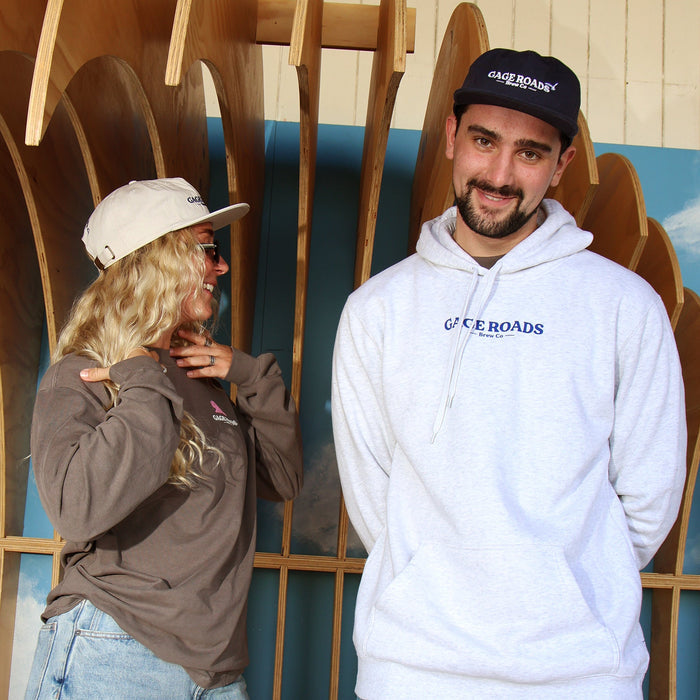 Two people standing on a large wooden surfboard with a decorative background.