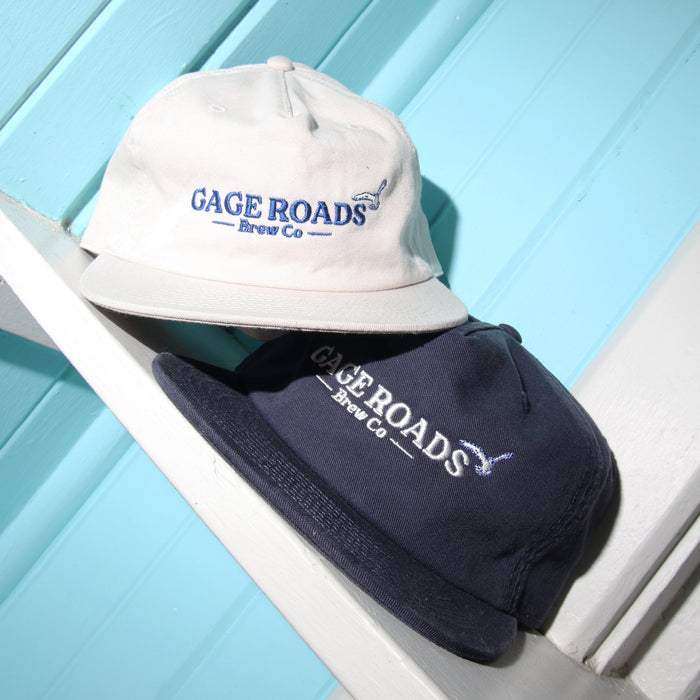 Two hats with 'Gage Roads Brew Co' branding on a light blue wooden surface.