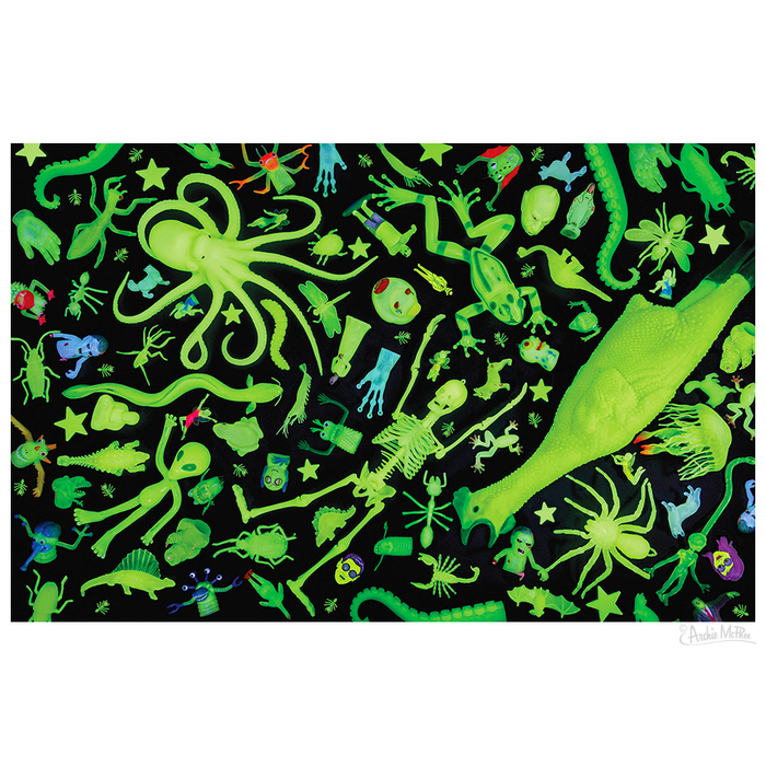 Discover the Glow Chamber Puzzle, a vibrant assortment of ghostly green toys and figures featuring animals, insects, and various shapes displayed against a dark background.