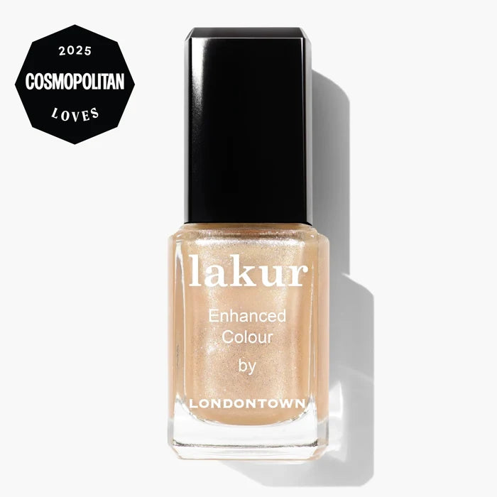 A bottle of LONDONTOWN Lakur Enhanced Colour nail polish in Isla Bonita, a shimmering gold beige, featuring a "2025 Cosmopolitan Loves" badge in the top left corner.