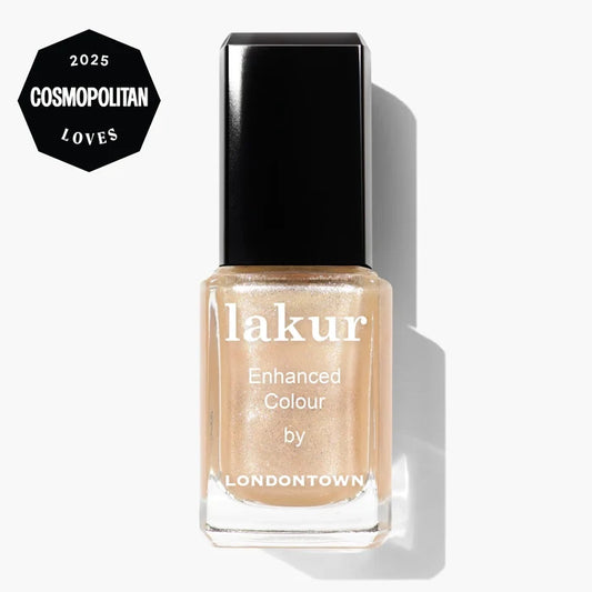 A bottle of LONDONTOWN Lakur Enhanced Colour nail polish in Isla Bonita, a shimmering gold beige, featuring a "2025 Cosmopolitan Loves" badge in the top left corner.