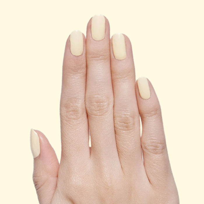 Hand with nails coated in JLR pastel sunny yellow gel polish for a cheerful and smooth manicure by Olive and June