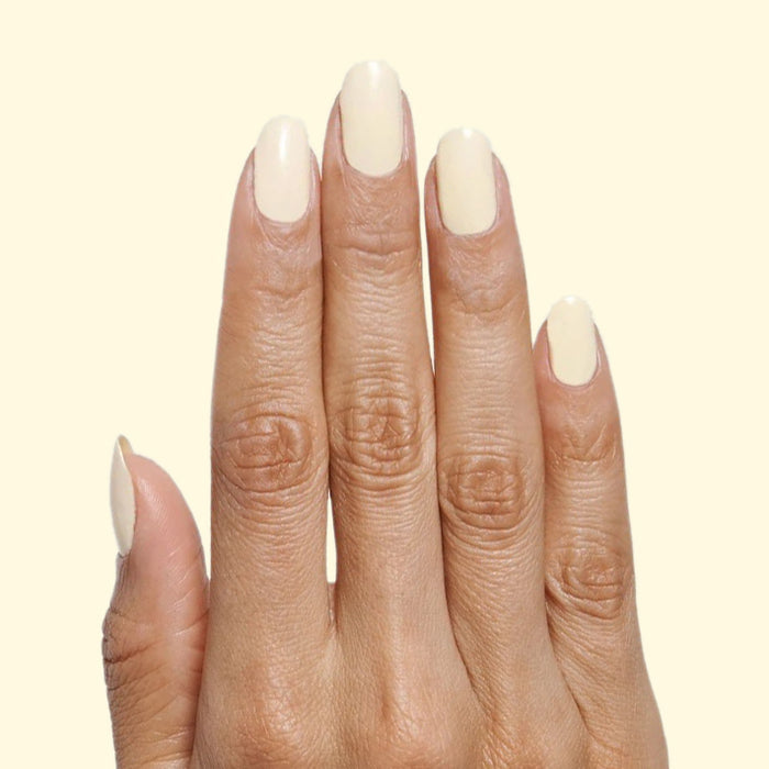 Hand with nails coated in JLR gel polish in soft pastel sunny yellow for a smooth mani by Olive and June
