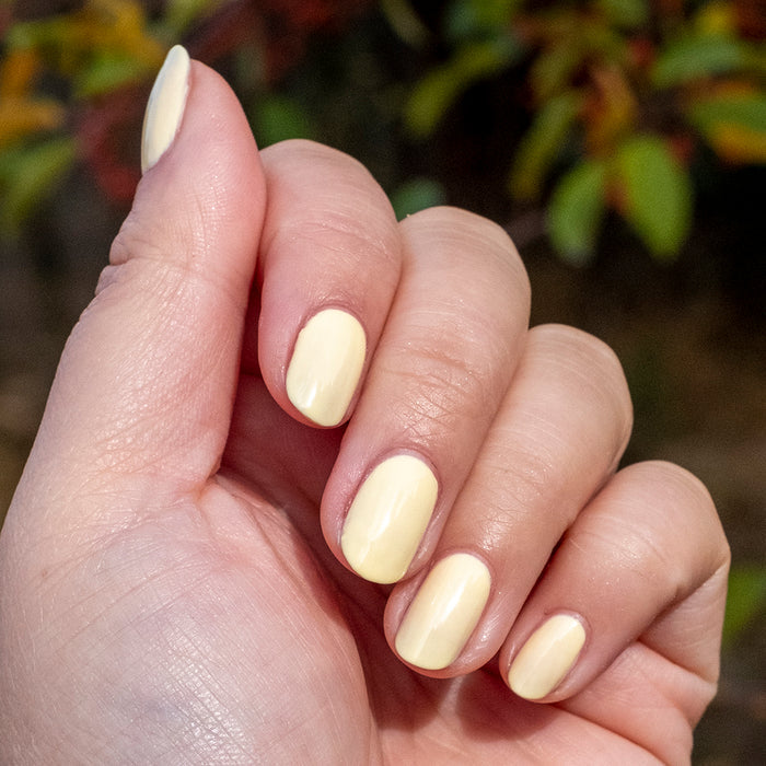Hand with nails painted in JLR gel polish, a soft pastel yellow shade for a fresh and cheerful manicure by Olive and June