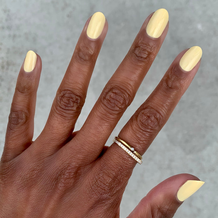 Hand with nails painted in JLR gel polish creamy pastel yellow for a smooth and sunny at-home manicure by Olive and June