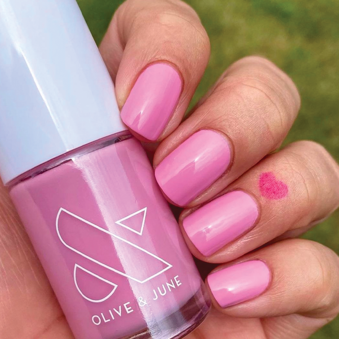 Hand holding JM nail polish bottle with nails painted in a vibrant pinky lavender gel polish by Olive and June
