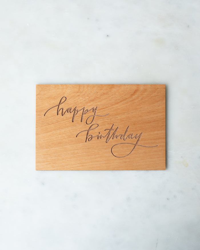Wooden postcard with “Happy Birthday” engraved in a calligraphic script.