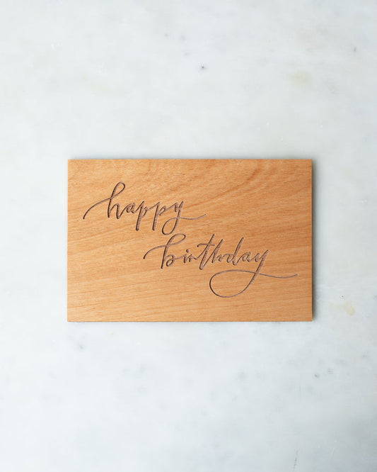 Wooden postcard with “Happy Birthday” engraved in a calligraphic script.