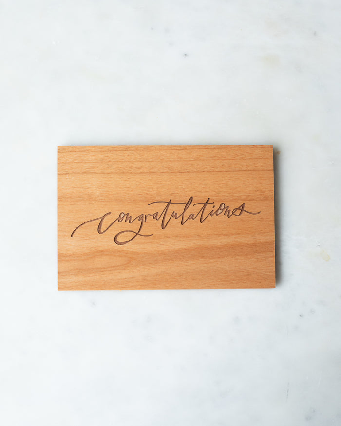Wooden postcard with “Congratulations” engraved in a calligraphic script.
