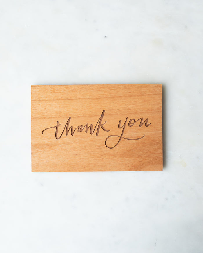 Wooden postcard engraved with “Thank you ” in a calligraphic script.