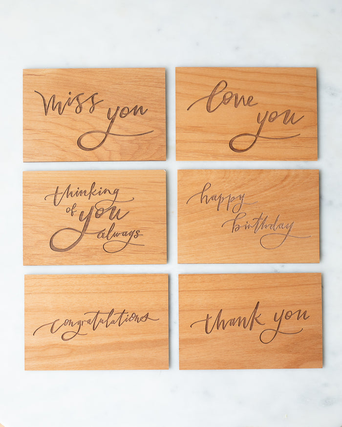 Set of six wooden postcards engraved in a calligraphic script with the messages: miss you, love you, thinking of you always, happy birthday, congratulations, and thank you.
