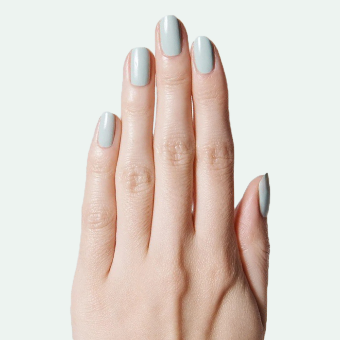 Hand with nails painted in soft sage green KMC gel polish for a smooth and natural manicure look