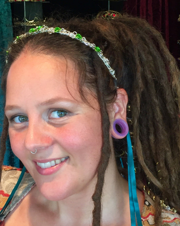Model wearing a silver wire floral crown headband with green rose accents and flowing ribbons.