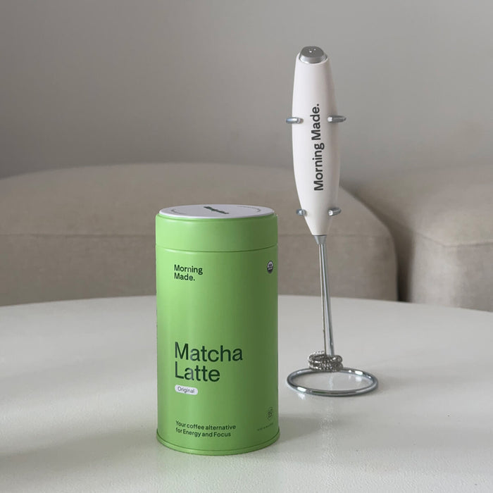 Morning Made Modern Matcha Whisk next to matcha latte tin on table.