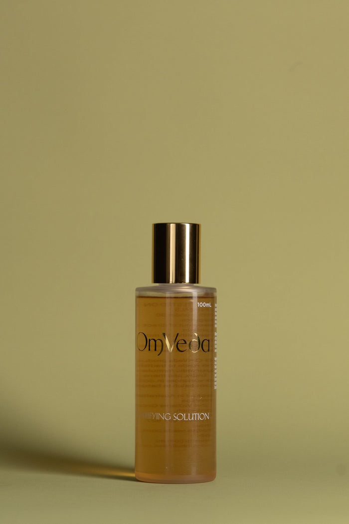 OmVeda clarifying solution bottle with gold cap and amber liquid