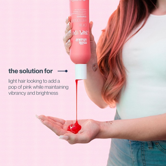 Person with pink hair holding a pink bottle of milk_shake hair color product against a pink background.