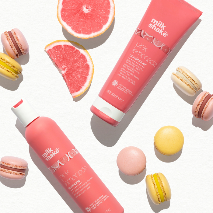 milk_shake Pink shampoo and conditioner bottles with macarons and grapefruit slices on a white background