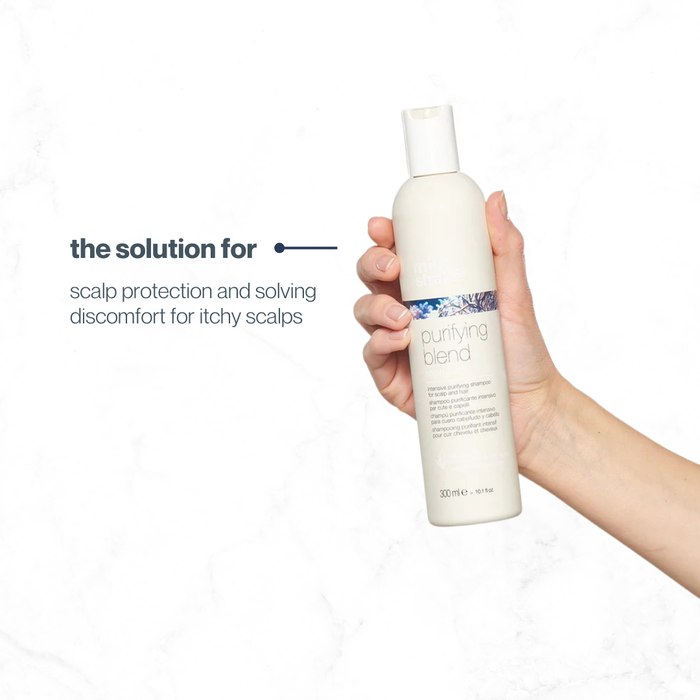 Hand holding a bottle of 'milk_shake purifying blend' scalp care product on a white background