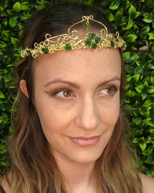 Model wearing Royal Rose Crown gold floral headpiece with green rose accents and crystal drop, front view.