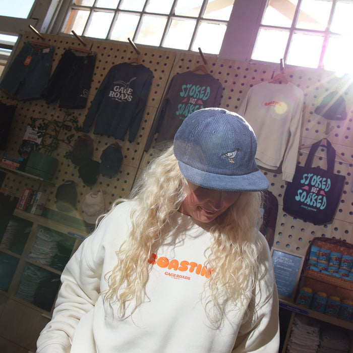 Person wearing a white sweatshirt with orange text in a store setting with merchandise on display.